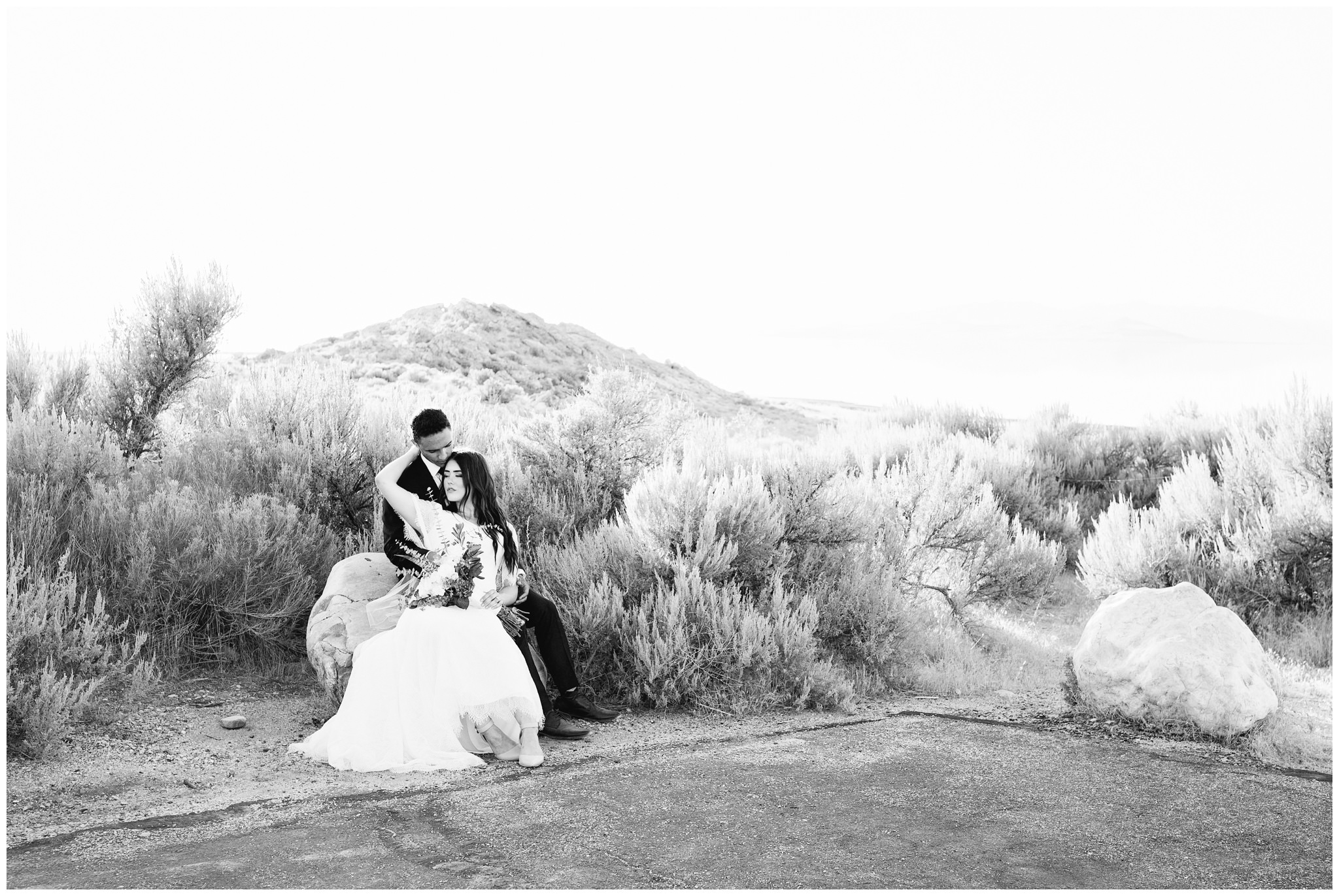 Bride and groom sitting on a rock snuggling at Lady finger point on Antelope island in Utah near SLC