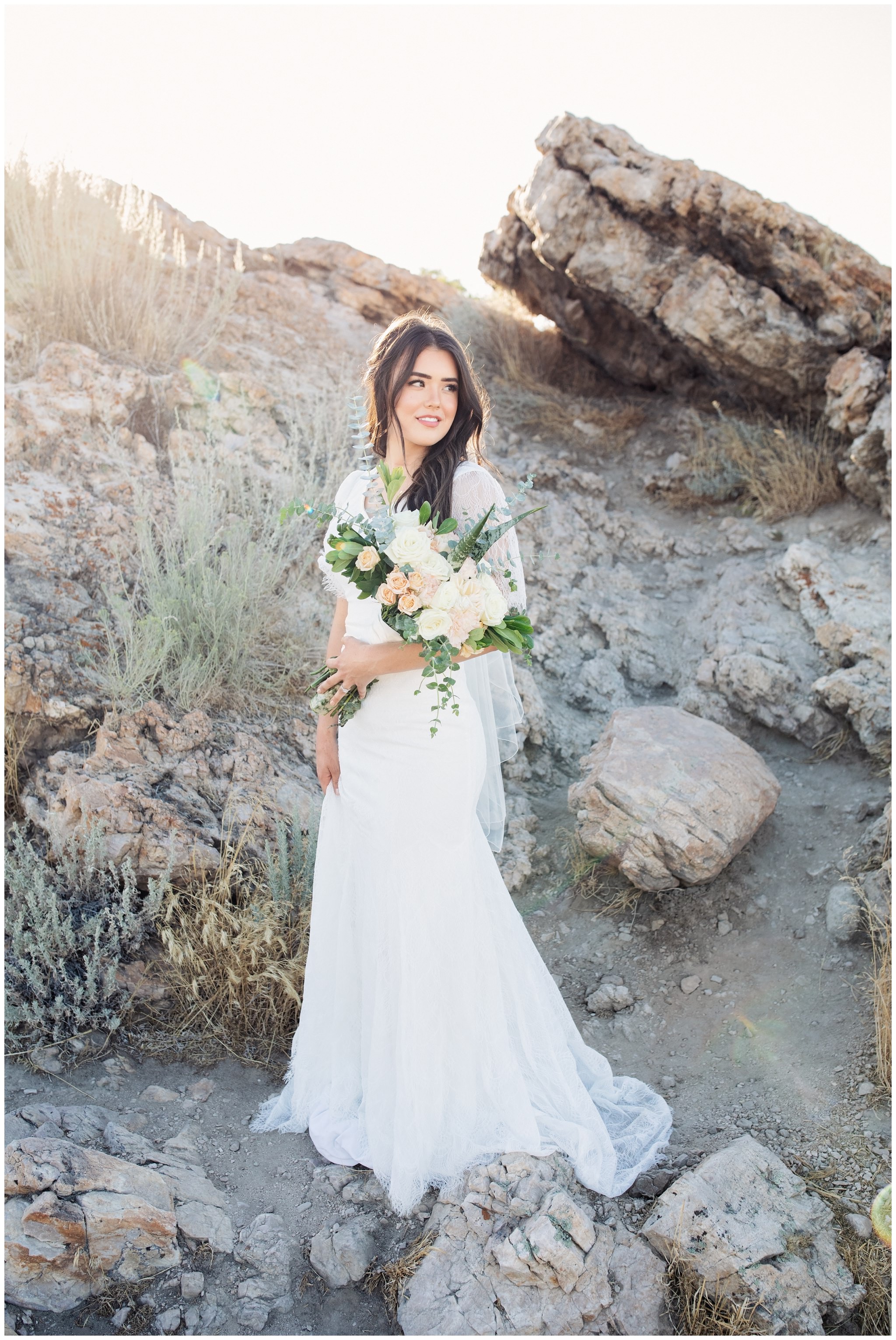 Bride's pictures of her holding wedding bouquet looking off in the distance near rocky background in Utah
