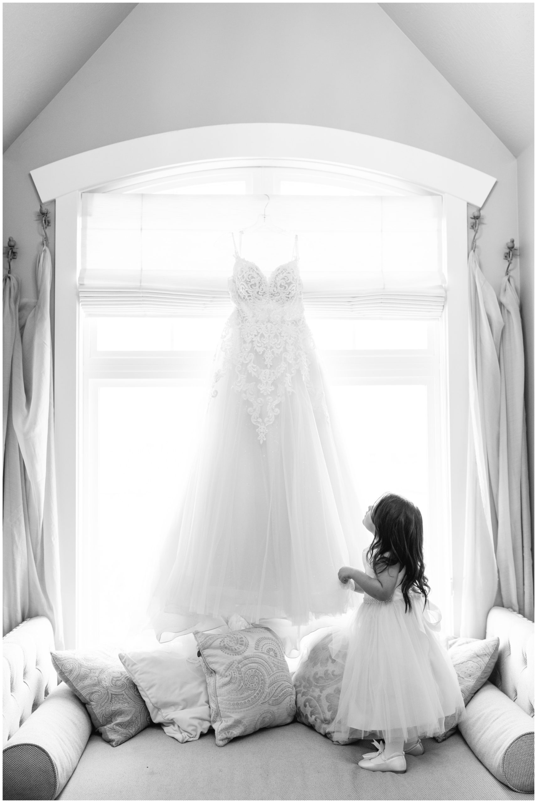 Young daughter looking at her mom's dress hanging in window at Sleepy Ridge in Vineyard Utah
