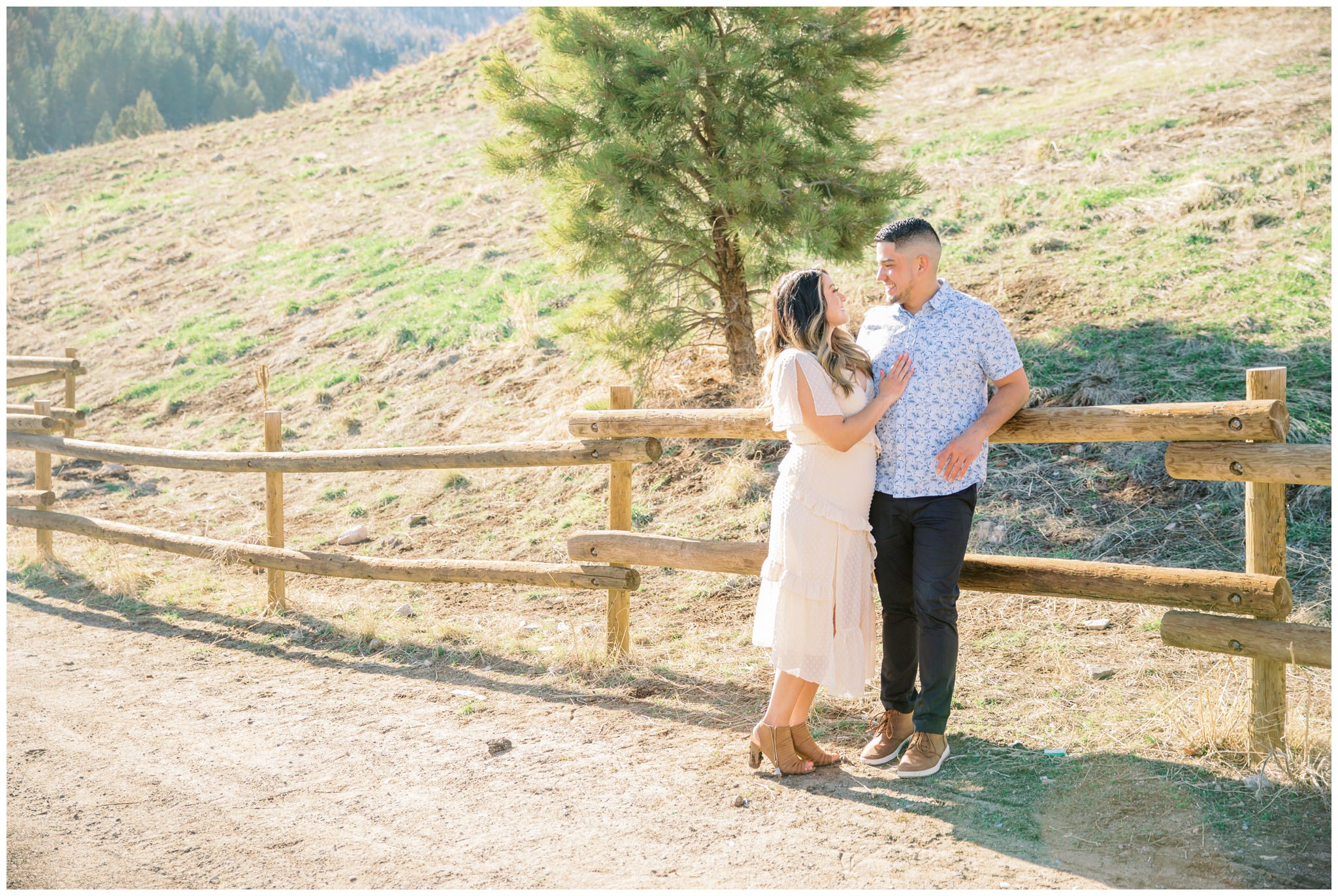 Bride and groom leaning against a wooden fence in the mountains for their engagement pictures in Utah