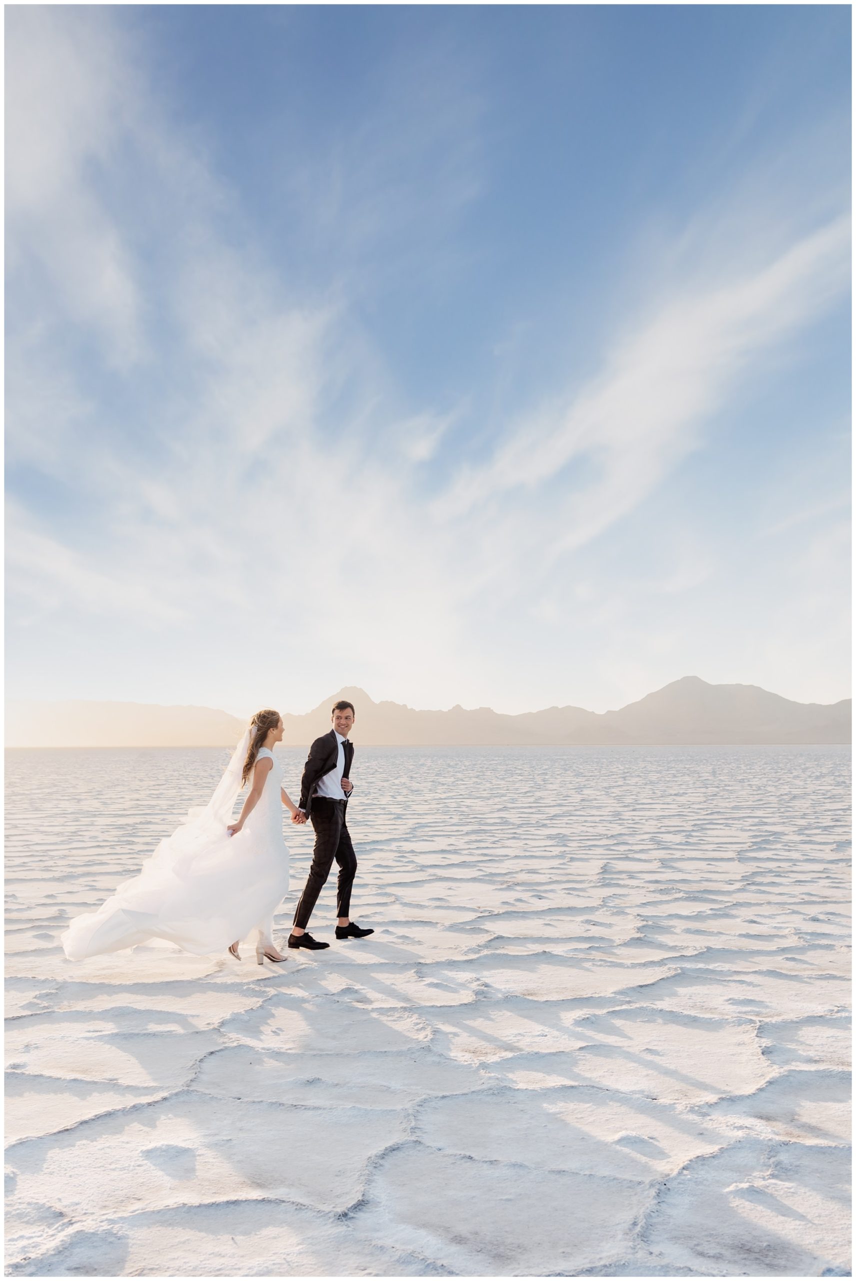 Bride and groom walking towards the sunset at the Salt Flats
